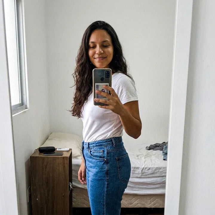 Selfie de perfil no espelho, de calça jeans de cintura alta