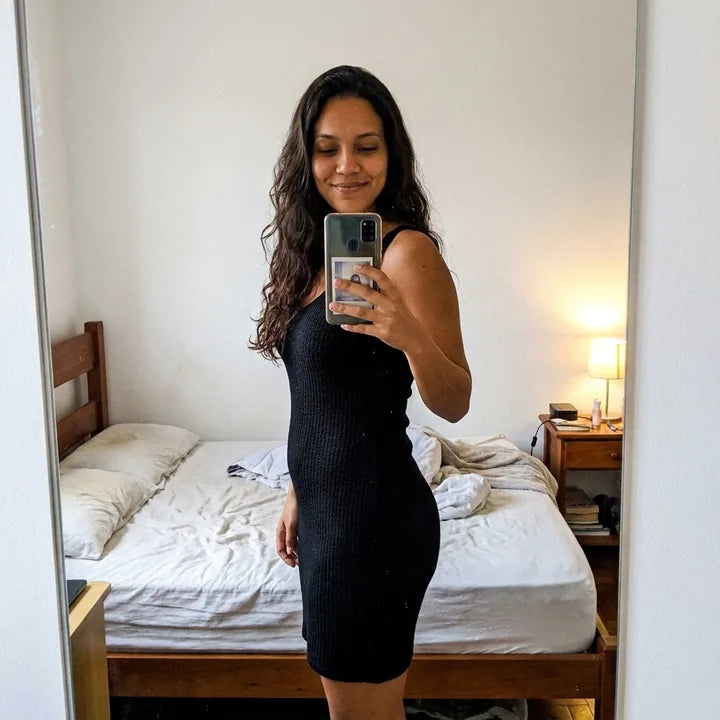 Selfie de perfil no espelho, de vestido preto justo, antes de sair