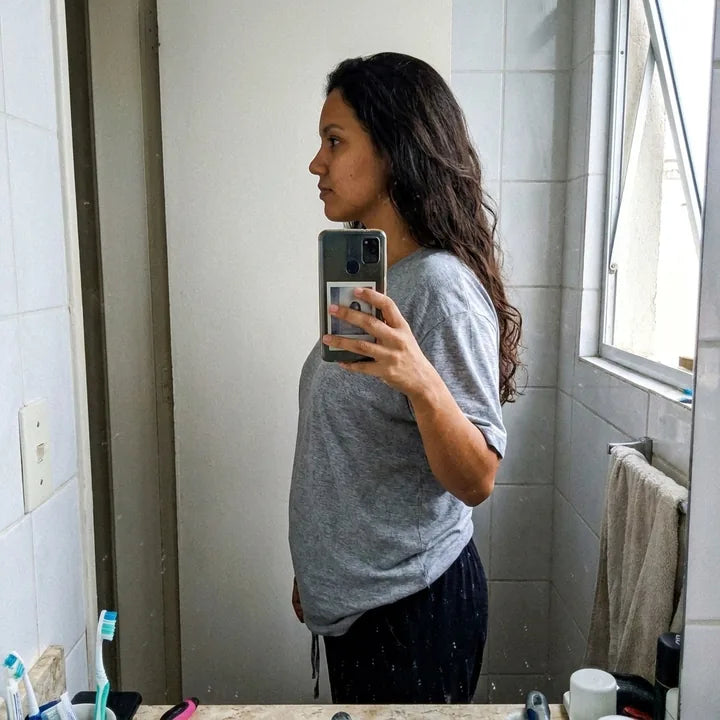 Selfie de perfil no espelho do banheiro, de camiseta cinza e calça de pijama