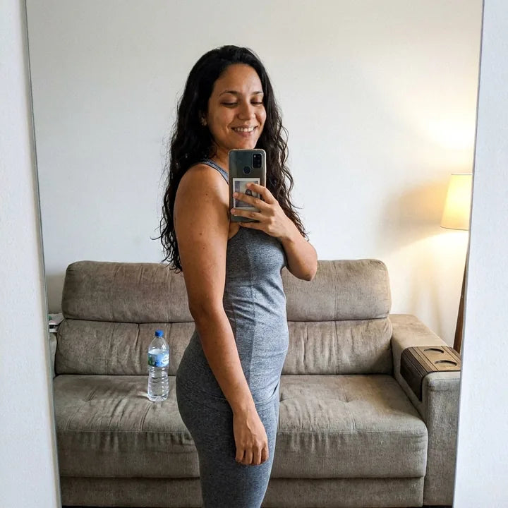 Selfie de perfil no espelho da sala, de legging e regata depois do treino